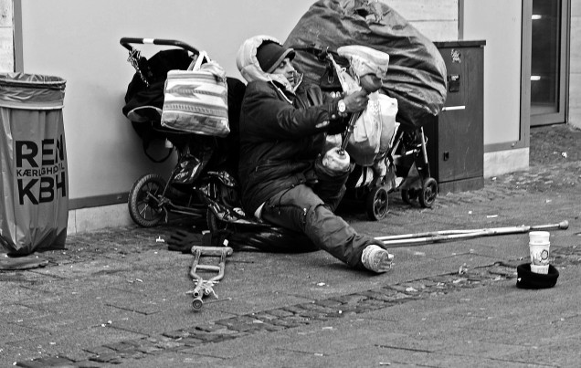 In one of the busy walking streets in Copenhagen I spotted this poor soul struggling to get a shoe on his prosthesis. It is a wonder, that he can manage the trolley and pram with his modest belongings. The filth on the pavement contrasts sharply with the litter bin, that proclaims "Pure love for Copenhagen" Camera Nikon D7100 